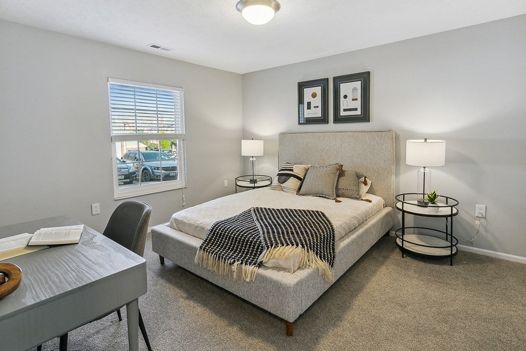 A bedroom with a bed, nightstand, and chair at The Donovan Apartment Homes, Nebraska