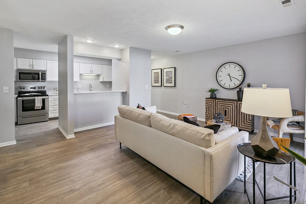an open living room and kitchen with a large clock on the wall at The Donovan Apartment Homes, Lincoln