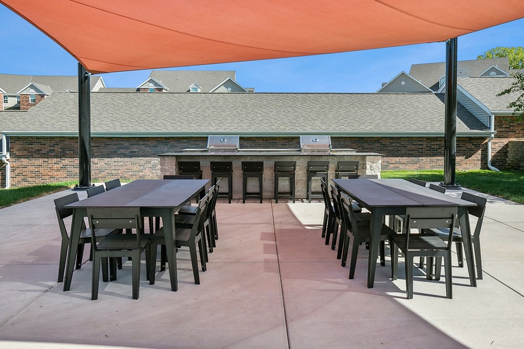 a patio with tables and chairs under an orange tent at The Donovan Apartment Homes, Lincoln, Nebraska
