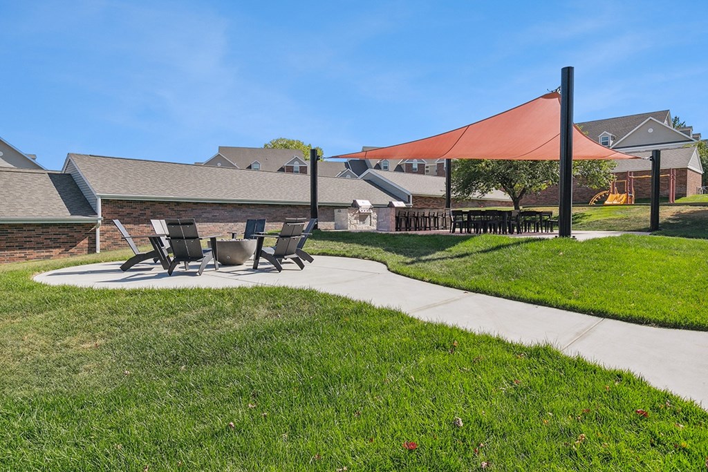 A patio with a table and chairs under a red shade structure at The Donovan Apartment Homes, Lincoln, NE