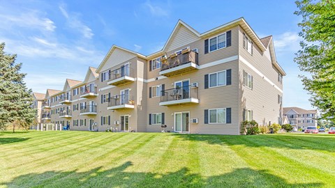 a large apartment building with balconies and a lawn