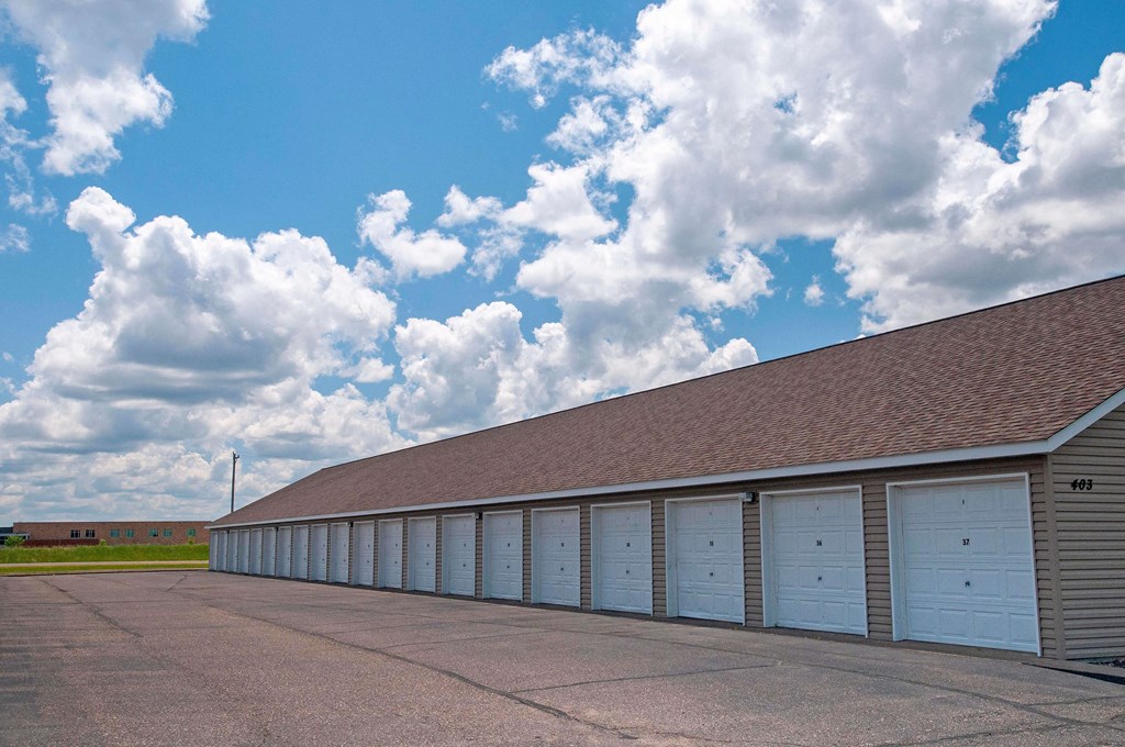 Detached garages with white doors and large driveway.