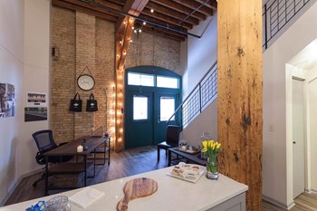 View of entryway from kitchen. Shows wood bean, exposed brick, and iron staircase. - Photo Gallery 8