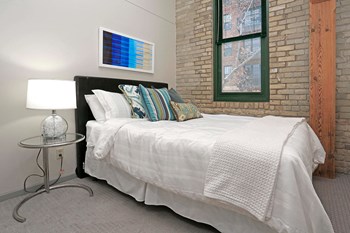 Side view of spacious bedroom with exposed brick wall and wood beam near window. - Photo Gallery 12