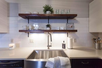 Exposed open shelving above large sink with stainless steel finishes. - Photo Gallery 9