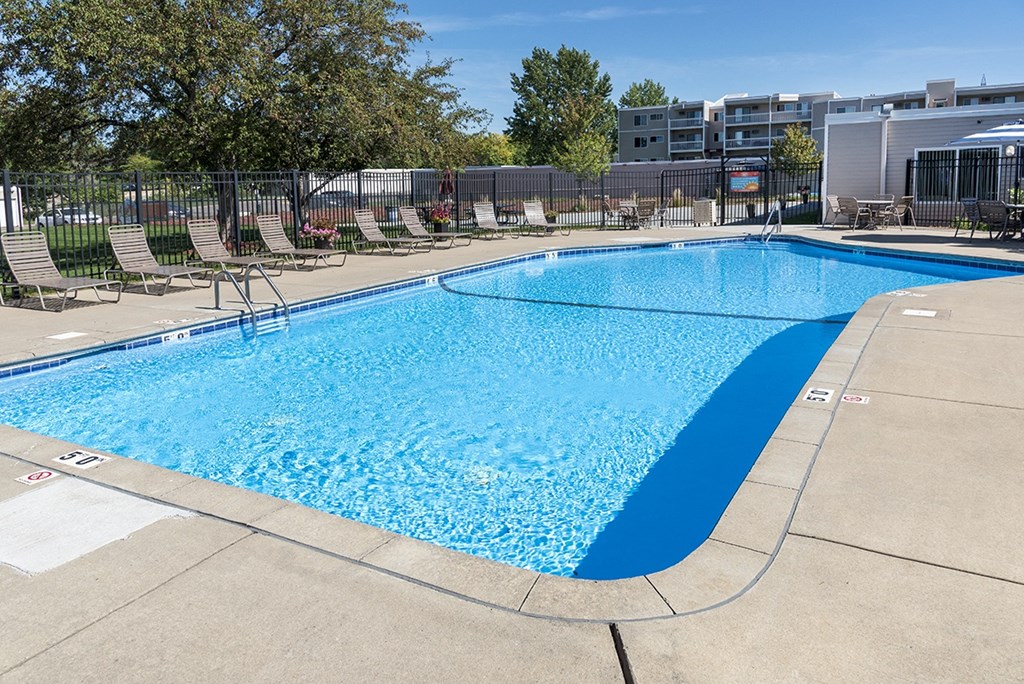a large pool with chairs and a fence around it