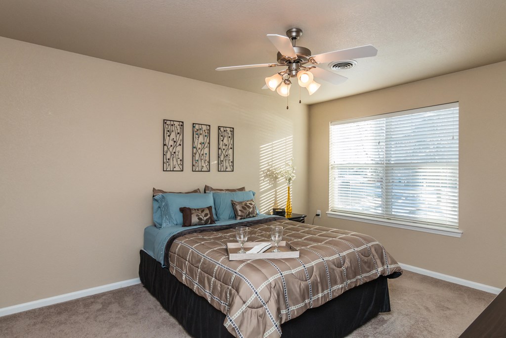 Spacious bedroom with a large window letting in natural light.