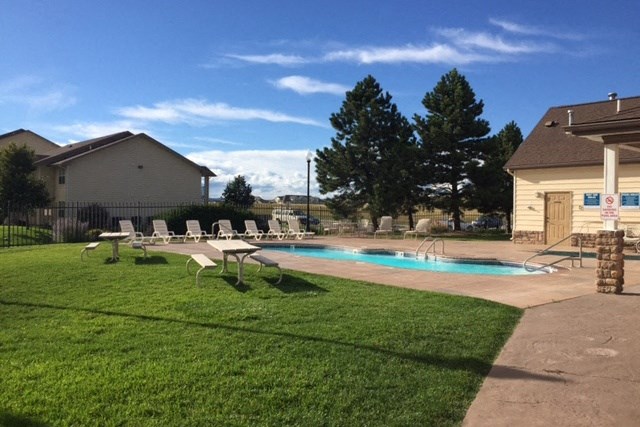 a backyard with a pool and lounge chairs