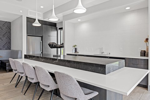 A modern kitchen with a marble countertop and grey chairs.