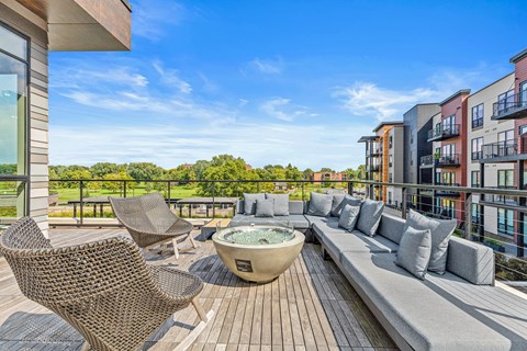 A patio with a hot tub and chairs overlooks a row of buildings.