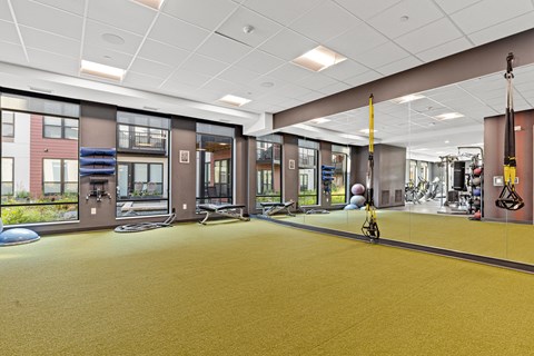 A gym with a yellow floor and various exercise equipment.
