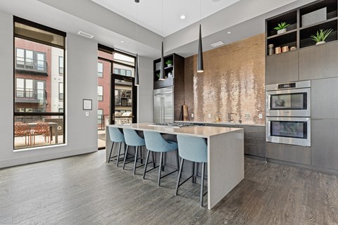 A modern kitchen with a long island and stools.