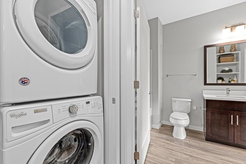 A Whirlpool washing machine is in a laundry room with a toilet and sink.
