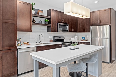 A modern kitchen with a white island and brown cabinets.
