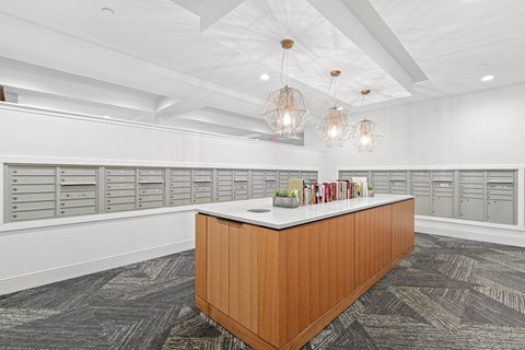 A reception desk with a white counter and a brown wooden frame is in the middle of a room with grey carpeting and white walls.