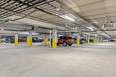 A parking garage with a red car parked in the middle.