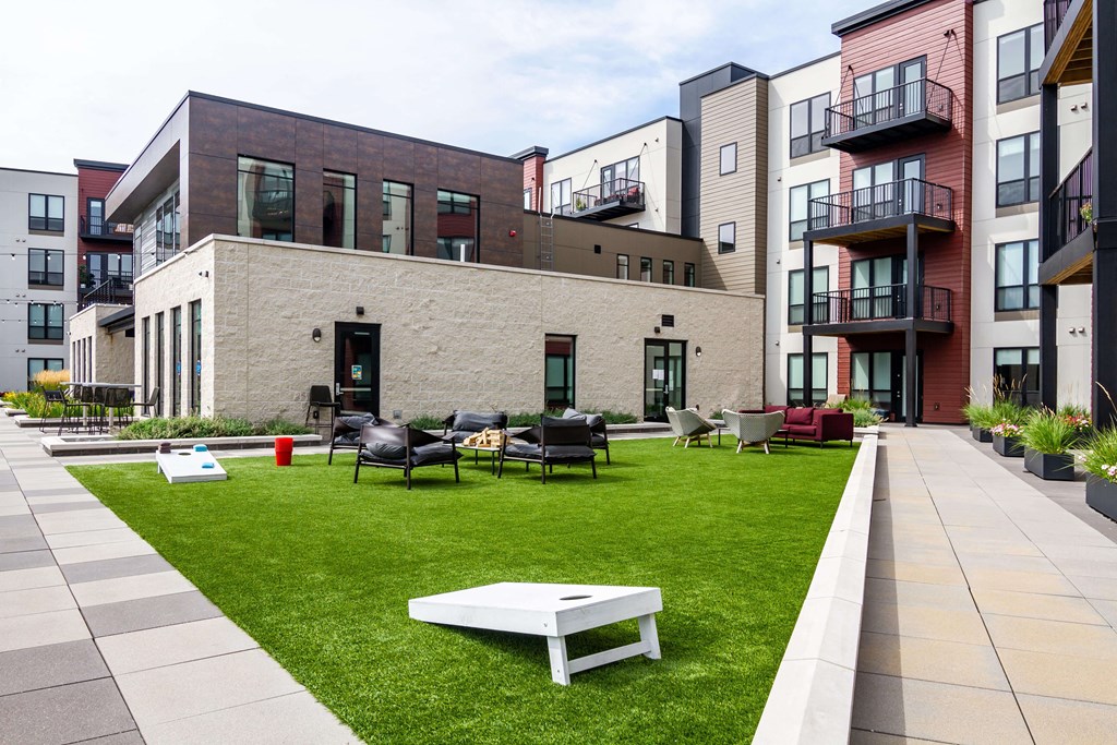 Large green space outlined by sidewalks with plenty of outdoor game options like cornhole.