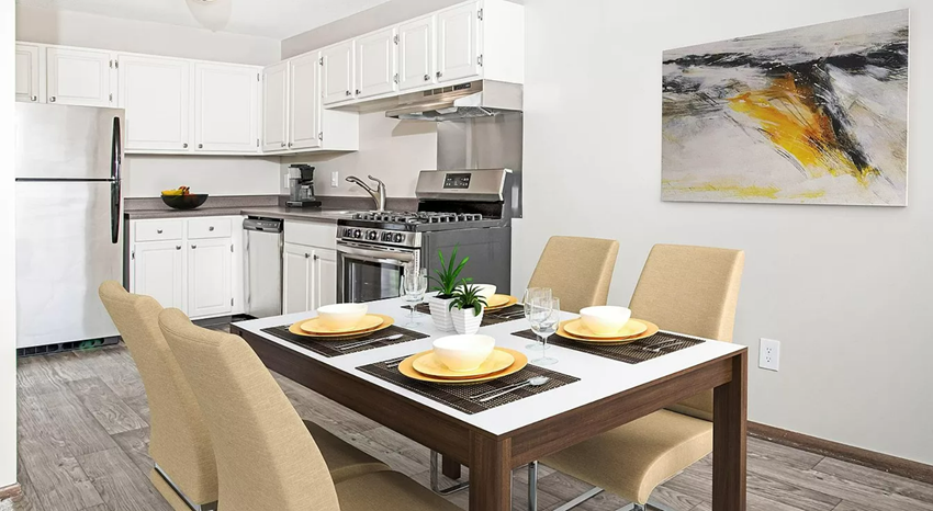 Modern white cabinet kitchen with stainless steel appliances and casual dining area with yellow chairs. - Photo Gallery 1