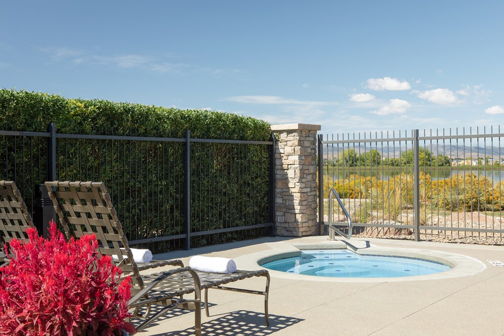 a jacuzzi and chairs on a patio next to a pool