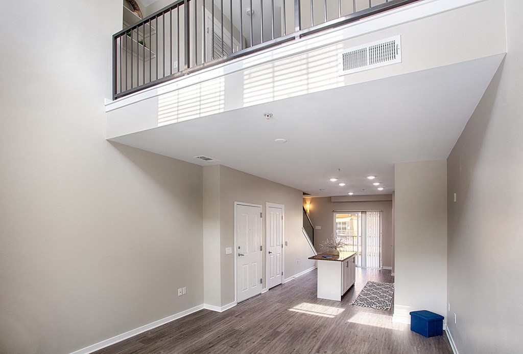a spacious living room with a balcony and a kitchen