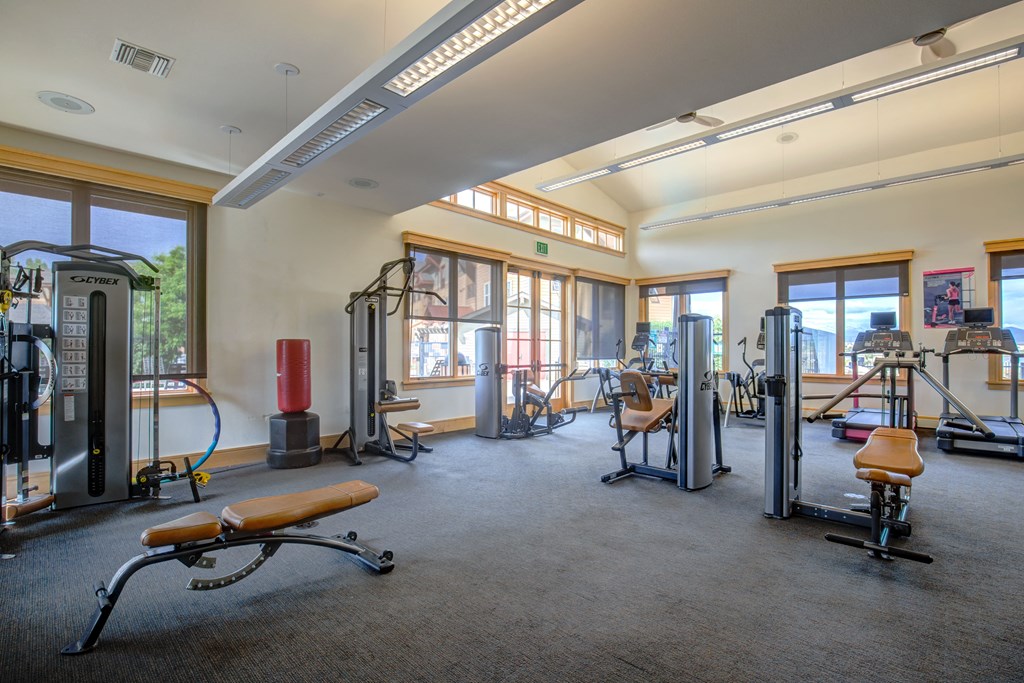 a large fitness room with exercise equipment and windows
