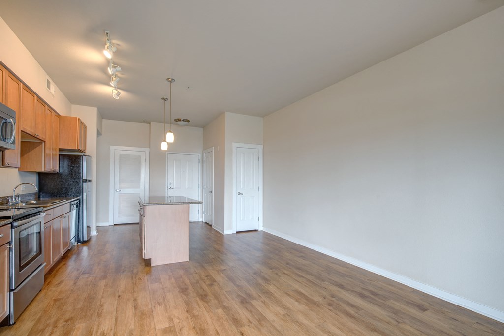a kitchen and living room with hardwood floors and white walls