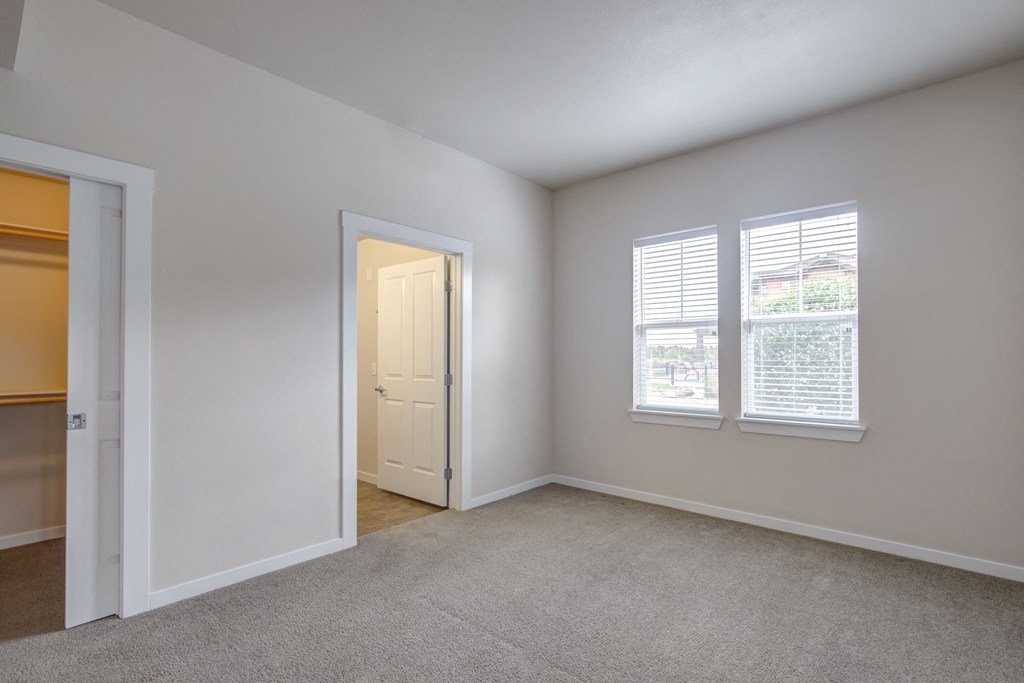 a bedroom with two windows and an open door