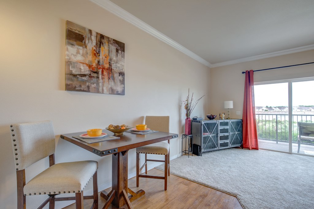 a dining area with a table and chairs and a sliding glass door leading to a balcony