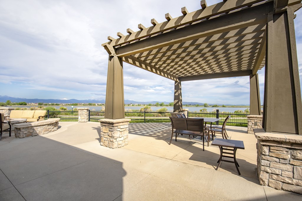 a patio with a pergola and a view of the water