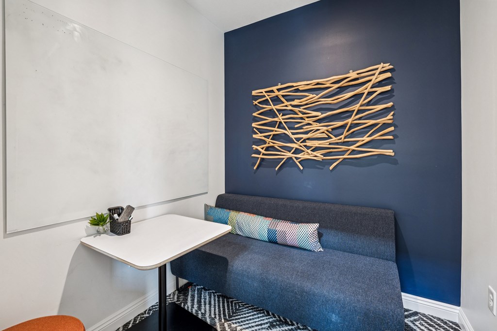 A blue couch with a white table and a wall art.
