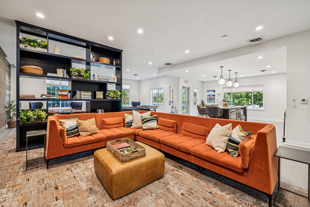 A living room with a large orange sofa and a coffee table in front of a bookshelf.