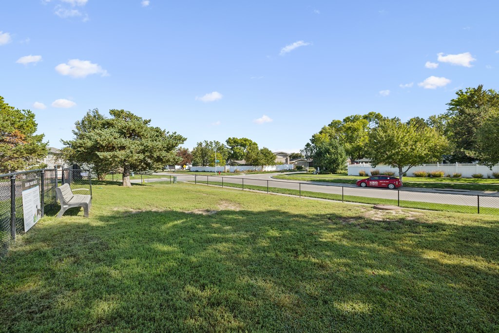 A park with a bench and a fence.