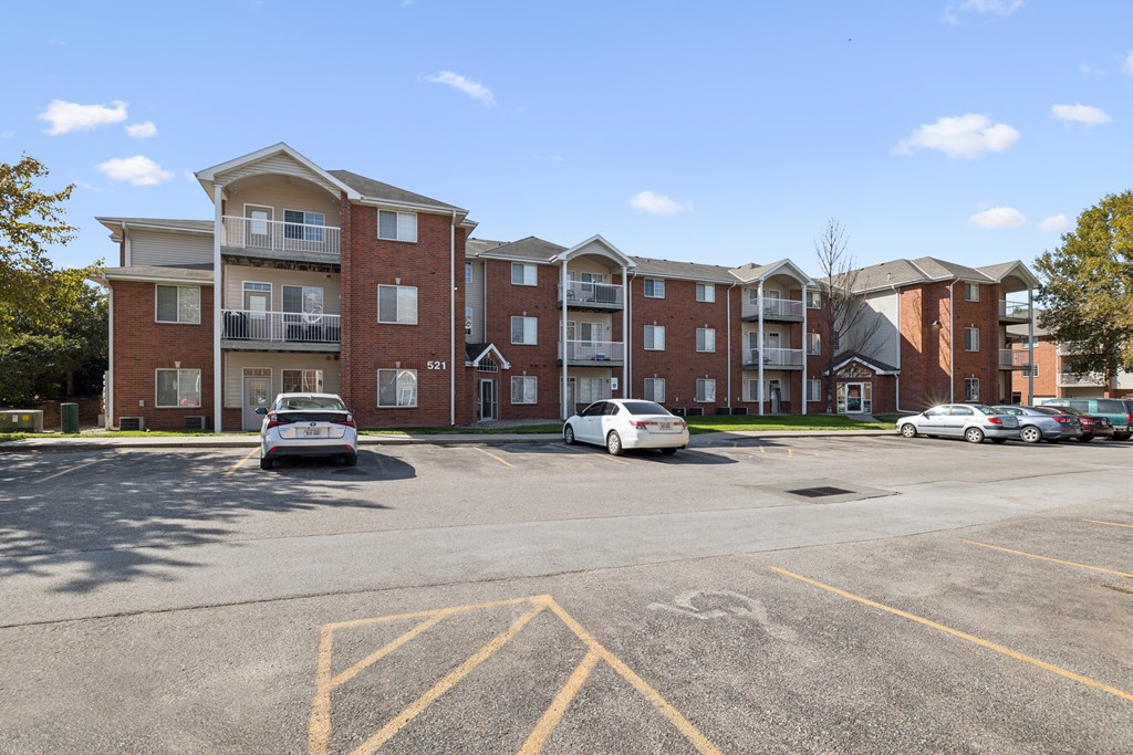 A parking lot in front of a red brick apartment building.