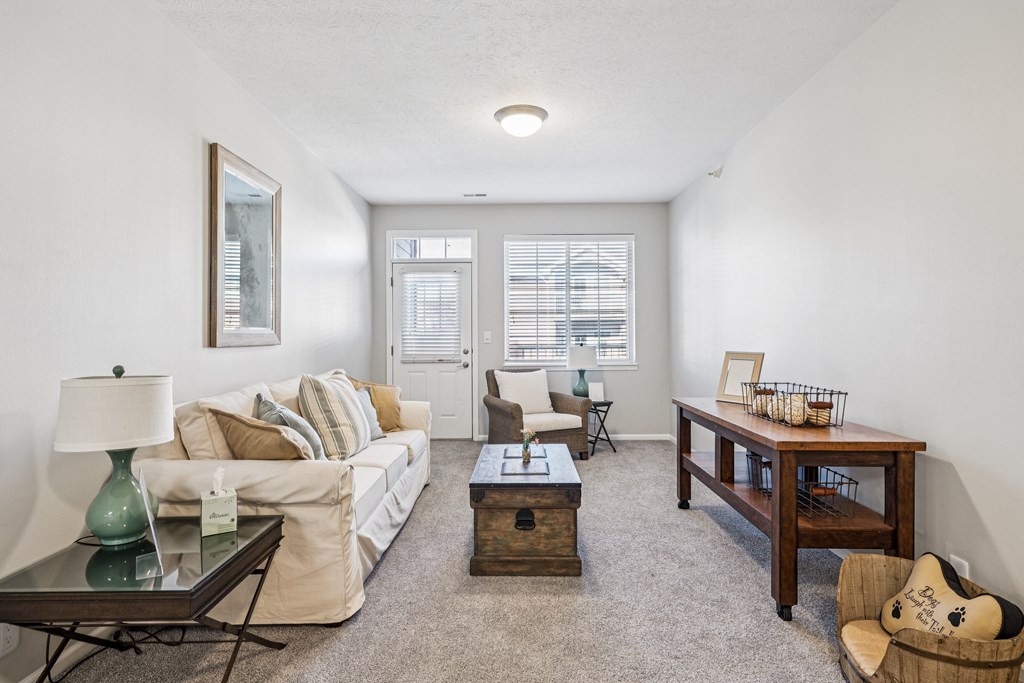 A living room with a white couch, a coffee table, and a chair.