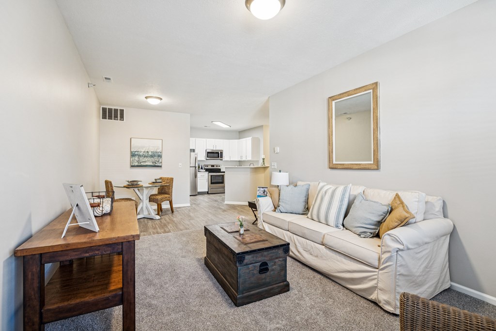 A living room with a couch, coffee table, and a dining table.
