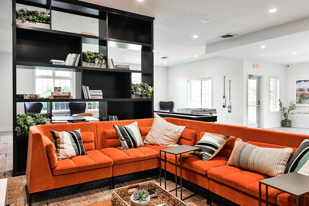 a living room with an orange couch and a black and white kitchen