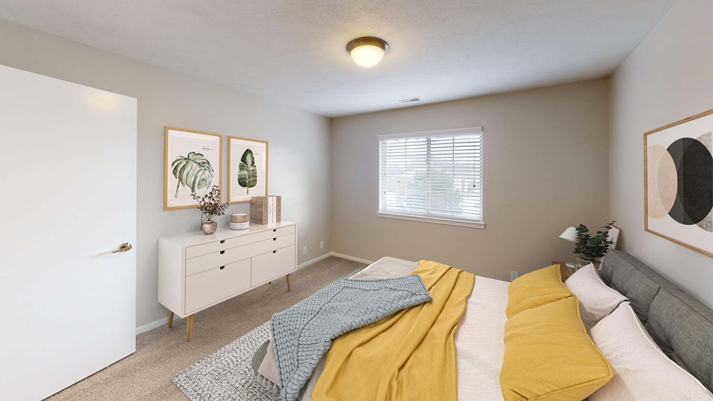 Spacious bedroom with a large window letting in natural light.