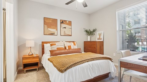 A bedroom with a bed, nightstand, and a ceiling fan.