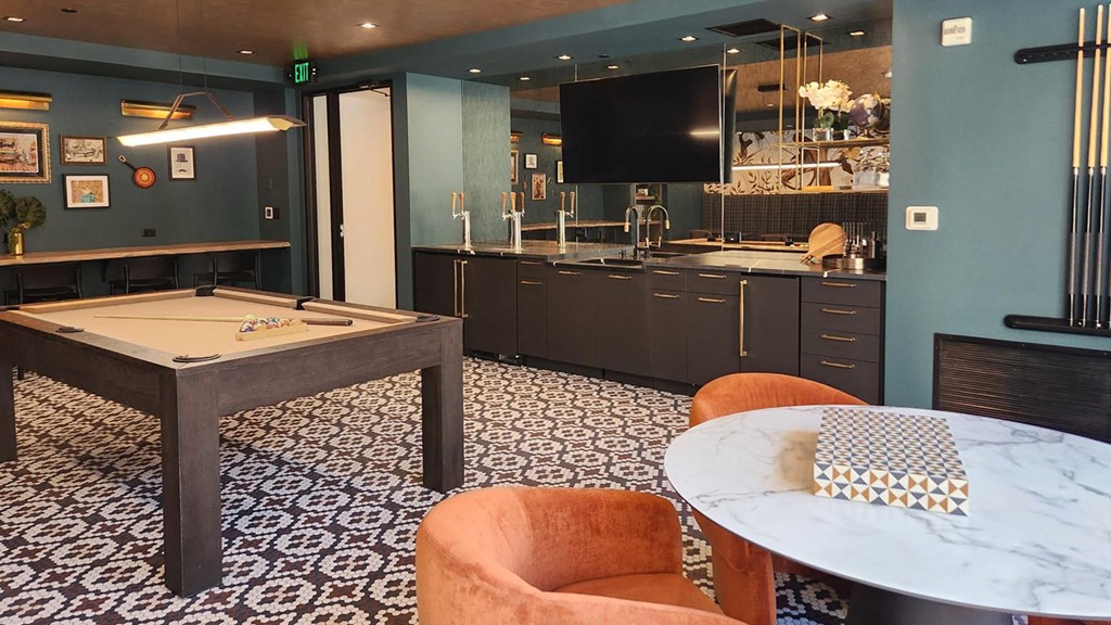 a game room with a pool table and a kitchen