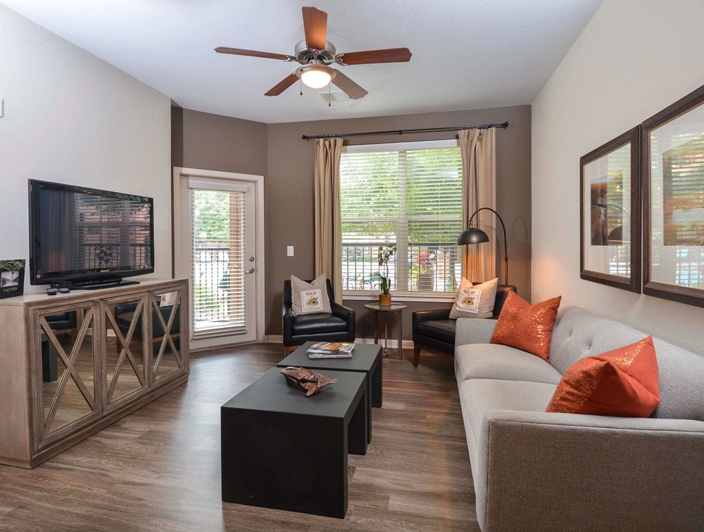 bright, furnished living room with television and door to patio
