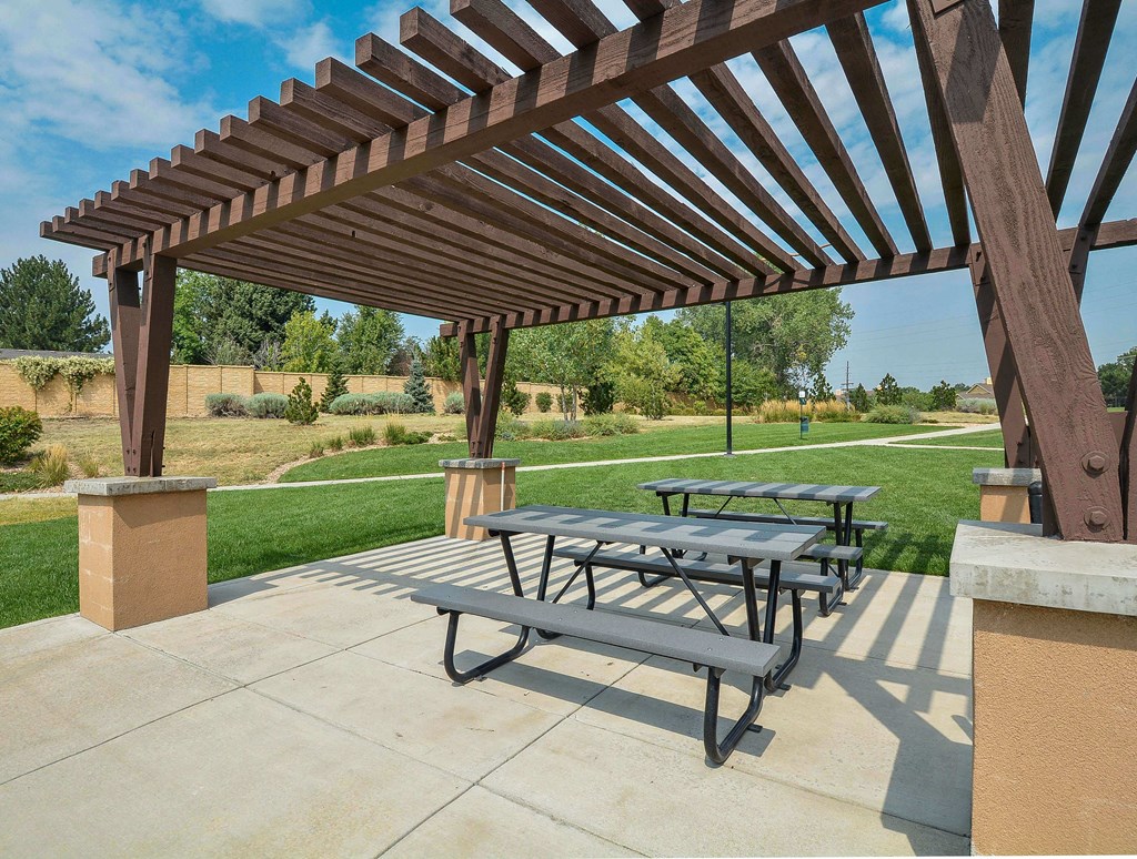 Outdoor picnic area underneath a pergola near the private walking path.
