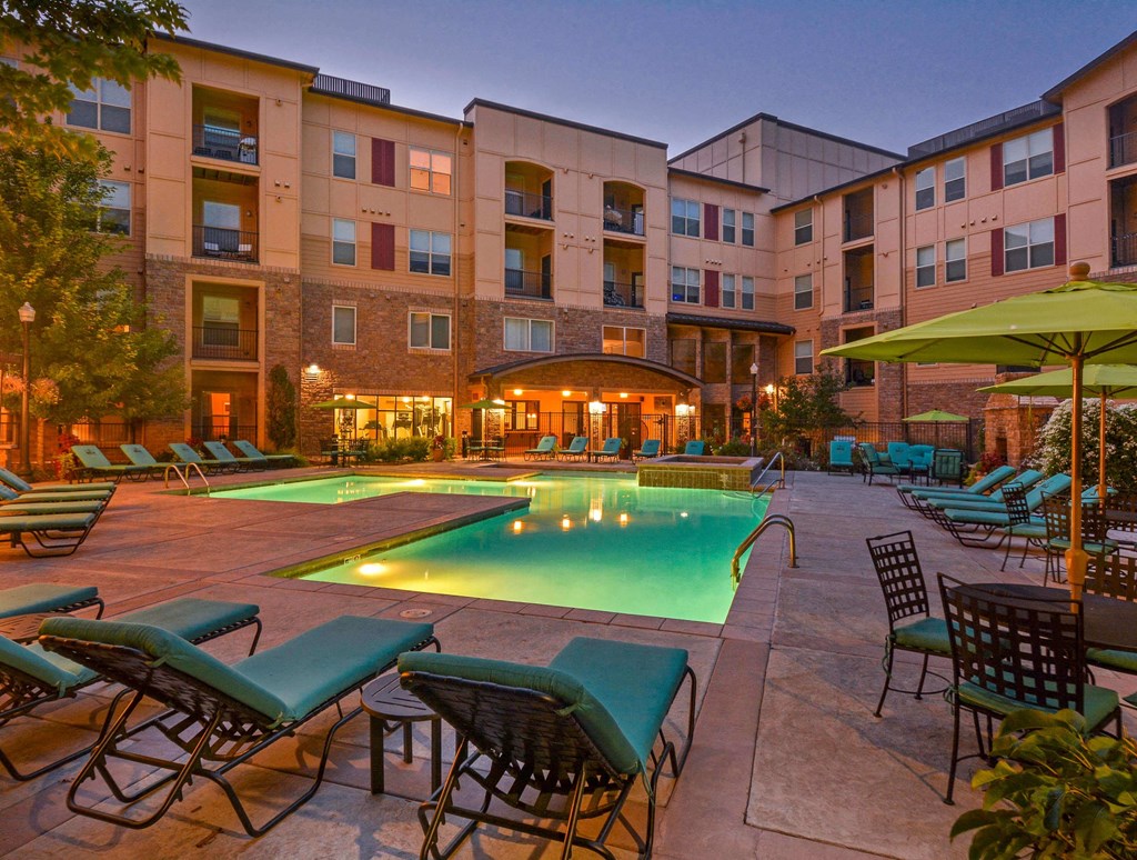 Gorgeous outdoor pool area with a heated pool, lounging chairs, and umbrella patio tables.