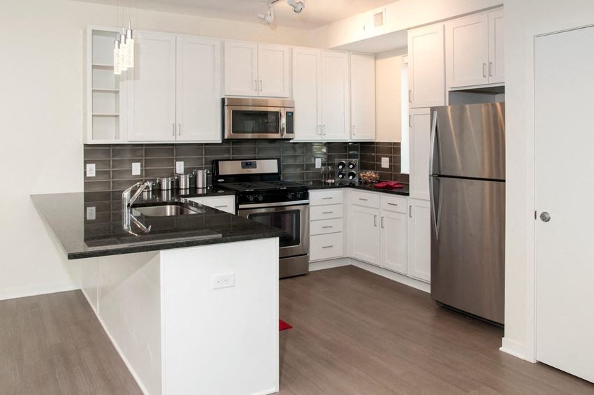 Kitchen with wood flooring, white finishes and dark granite countertops