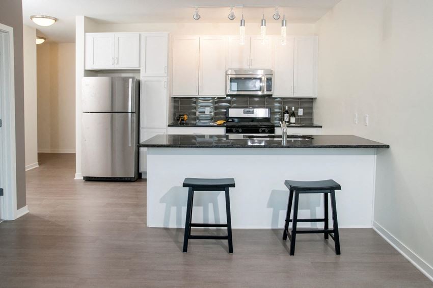 Open floor plan kitchen, with breakfast bar, white cabinet finishes and stainless steel fridge and microwave