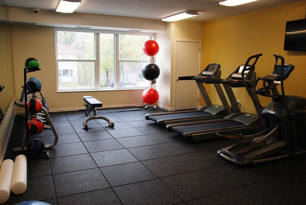 Fitness Room with rubber flooring, two treadmills, and medicine ball rack