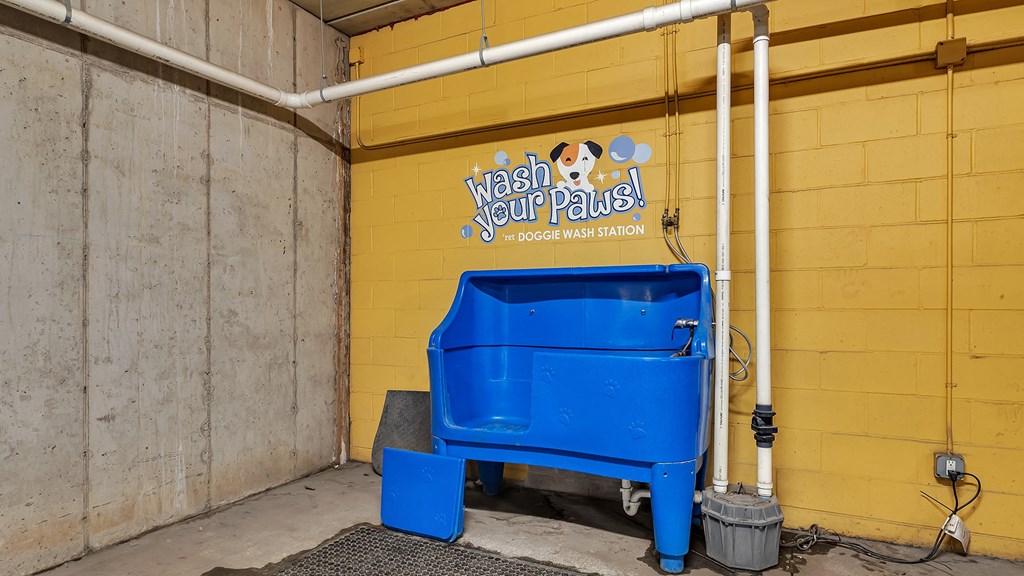 a blue trash can in front of a yellow wall