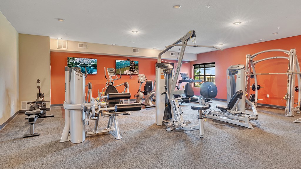 a gym with cardio equipment and weights on the floor