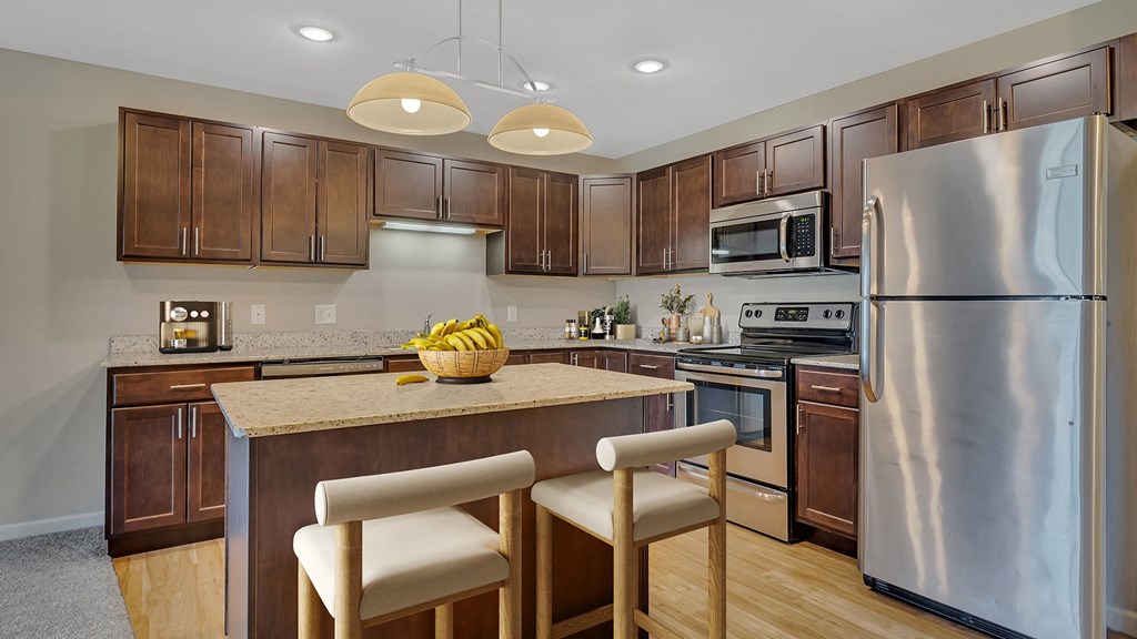a kitchen with stainless steel appliances and an island with chairs