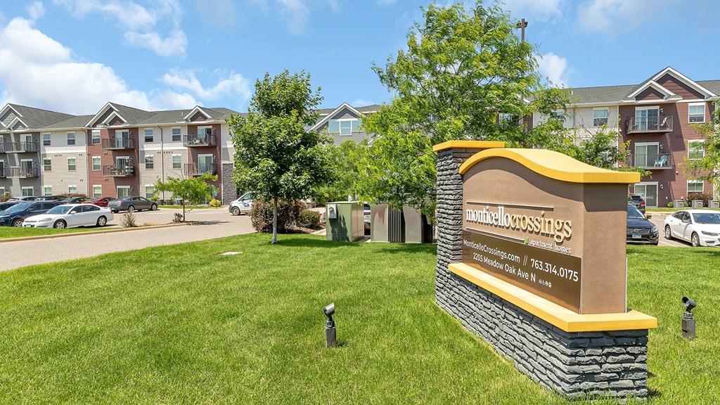 a sign in the grass in front of an apartment building