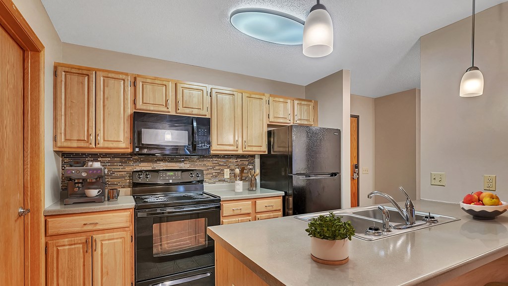 an updated kitchen with black appliances and wood cabinets